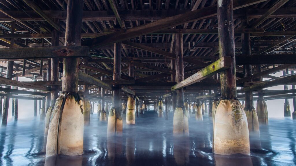 Stunning Under Pier Perspective with Misty Ocean Waves 4K Desktop Wallpaper