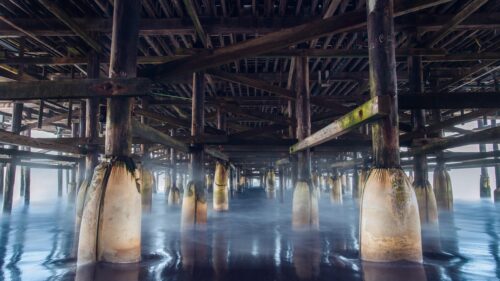 Stunning Under Pier Perspective with Misty Ocean Waves 4K Desktop Wallpaper