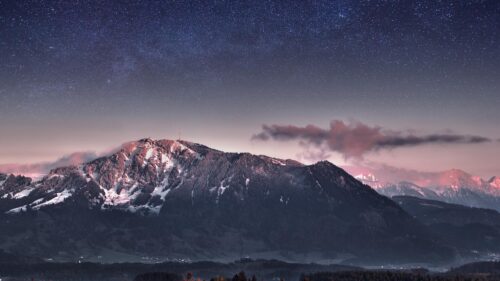 Majestic Snow Capped Mountain Peak Under a Starry Night Sky 4K Desktop Wallpaper