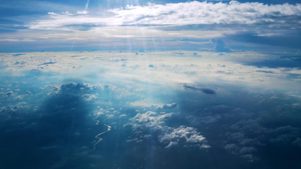 Sunlight Piercing Through Clouds Over Winding River Aerial View 4K Wallpaper