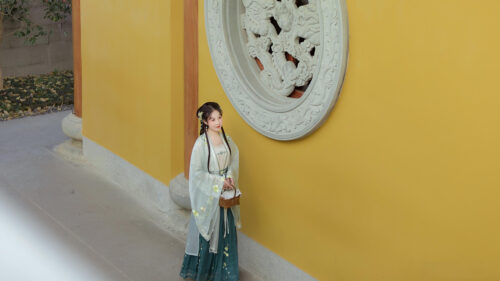 Elegant Woman in Traditional Hanfu Standing by Chinese Temple Wall 4K Wallpaper