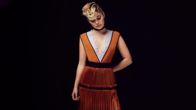 Olivia Holt Elegant Portrait in Burnt Orange Pleated Dress 4K Desktop Wallpaper