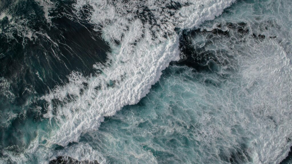 Aerial View of Deep Blue Ocean Waves and White Sea Foam Desktop Wallpaper