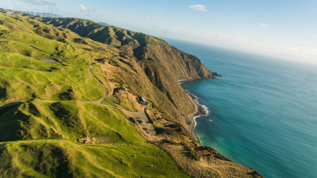 Stunning Aerial View of Lush Green Coastal Cliffs and Wind Turbines 4K Wallpaper