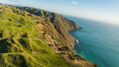 Stunning Aerial View of Lush Green Coastal Cliffs and Wind Turbines 4K Wallpaper