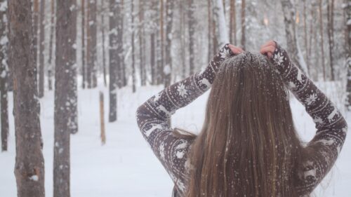 Woman Wearing a Patterned Winter Sweater in a Snowy Forest Desktop Wallpaper