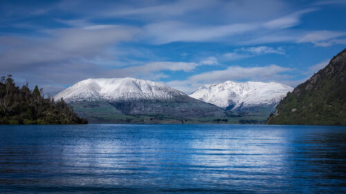 Breathtaking Snowy Mountain Peaks Over Blue Lake Desktop Wallpaper
