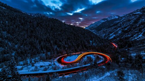 Stunning Winding Mountain Road with Red Light Trails at Winter Dusk 4K Wallpaper