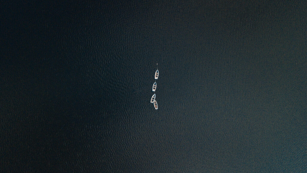 Minimalist Aerial View of Small Boats on Calm Dark Water 4K Desktop Wallpaper