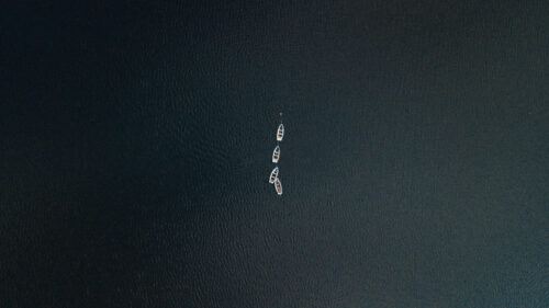 Minimalist Aerial View of Small Boats on Calm Dark Water 4K Desktop Wallpaper