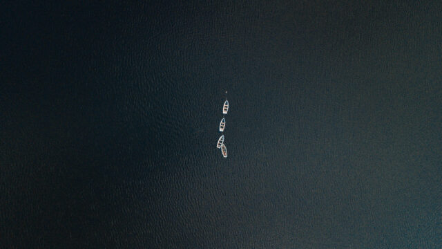 Minimalist Aerial View of Small Boats on Calm Dark Water 4K Desktop Wallpaper