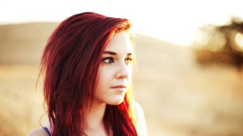 Beautiful Young Woman with Vibrant Red Hair in Golden Hour Sunlight 4K Wallpaper