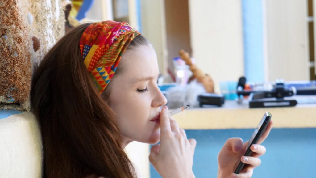 Candid Portrait of a Young Woman Smoking and Using Her Smartphone Desktop Wallpaper