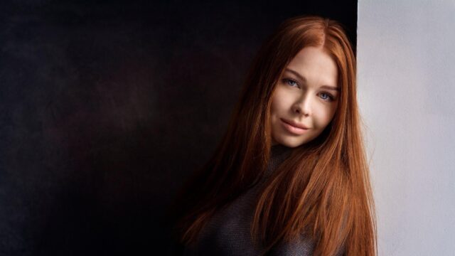 Stunning Portrait of a Woman with Long Red Hair Against Minimalist Background 4K Wallpaper