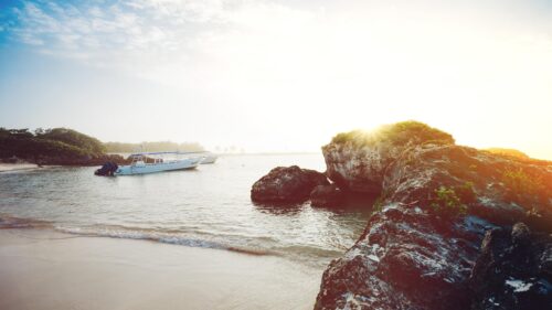 Serene Tropical Beach at Sunrise with Boats and Rocky Coast 4K Wallpaper