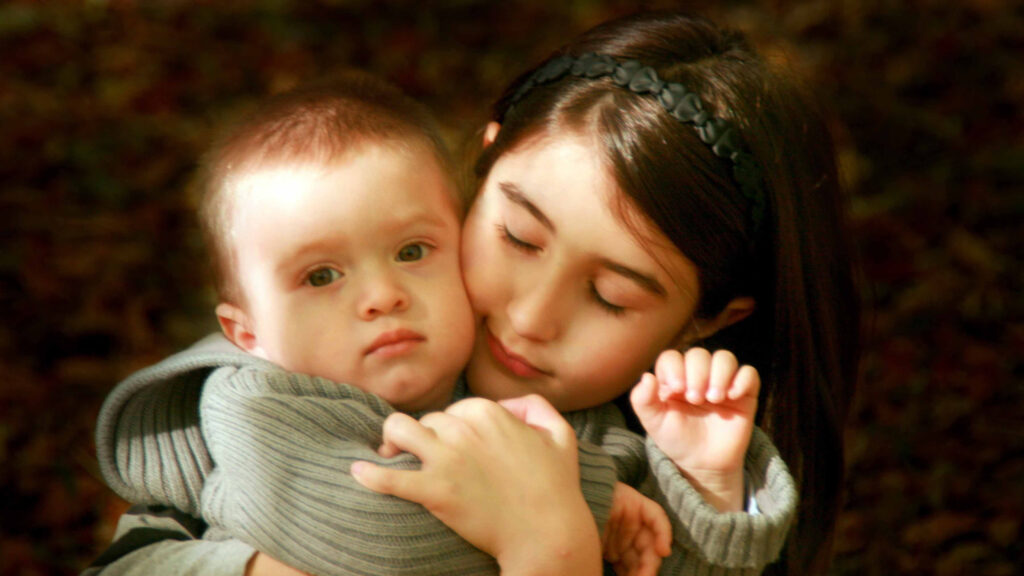 Affectionate Young Sister Hugging Her Baby Brother Desktop Wallpaper