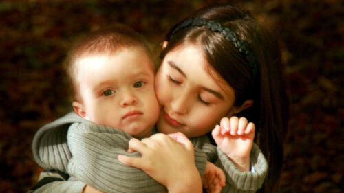 Affectionate Young Sister Hugging Her Baby Brother Desktop Wallpaper