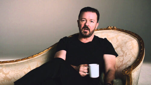 Comedian Ricky Gervais Resting on Ornate Sofa Desktop Wallpaper