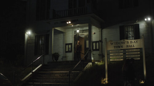 A Man Stands in the Entrance of a Dimly Lit Town Hall Desktop Wallpaper