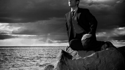 Black and White Portrait of a Man on a Rock Desktop Wallpaper