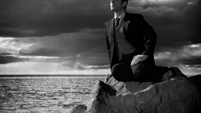 Black and White Portrait of a Man on a Rock Desktop Wallpaper