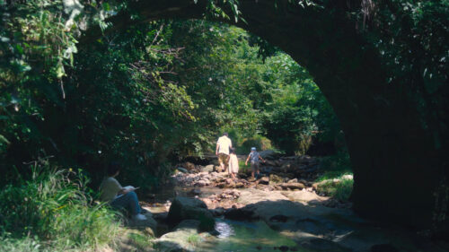 Family Exploring a Lush Creek Under a Stone Bridge Desktop Wallpaper