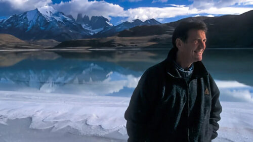 Man Standing by a Calm Mountain Lake Desktop Wallpaper