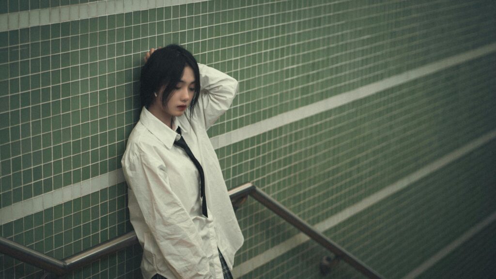Melancholic Asian Girl in White Shirt leaning on Green Tiled Wall Desktop Wallpaper
