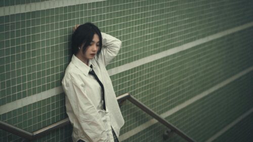 Melancholic Asian Girl in White Shirt leaning on Green Tiled Wall Desktop Wallpaper