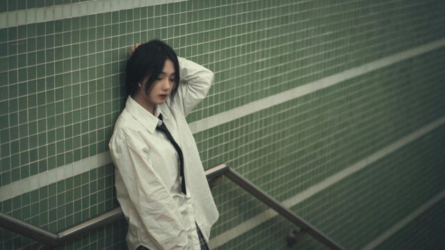 Melancholic Asian Girl in White Shirt leaning on Green Tiled Wall Desktop Wallpaper