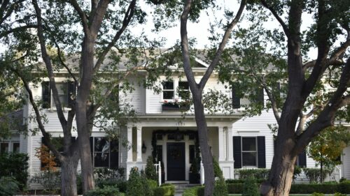 Stately White Colonial Home With Lush Green Trees Desktop Wallpaper