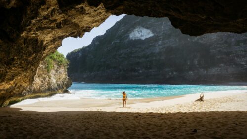 Woman Standing on Tropical Beach in Cave Entrance 4K Wallpaper
