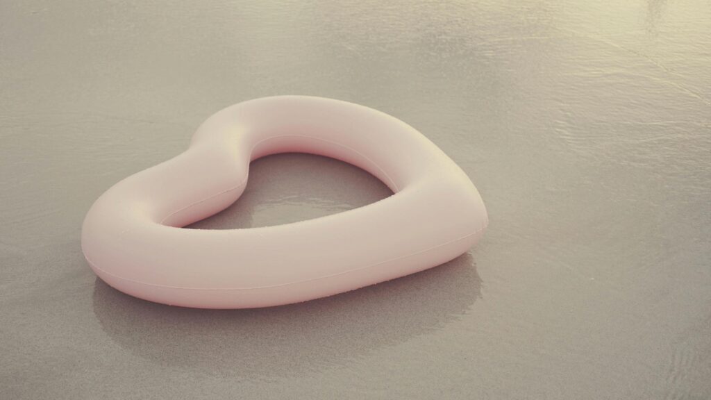Minimalist Pink Heart Pool Float on Sandy Beach Desktop Wallpaper