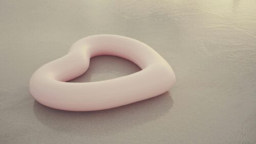 Minimalist Pink Heart Pool Float on Sandy Beach Desktop Wallpaper