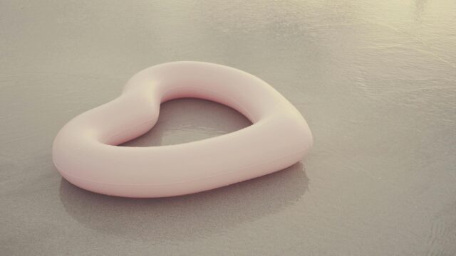 Minimalist Pink Heart Pool Float on Sandy Beach Desktop Wallpaper