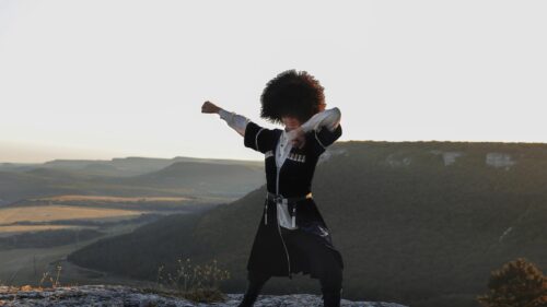 Caucasian Dancer in Traditional Chokha Outfit on Mountain Peak 4K Wallpaper