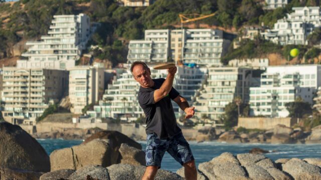 Man Playing Beach Paddle Ball by the Ocean Desktop Wallpaper
