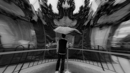 Man Holding Umbrella Under Ornate Carousel Black and White PC Wallpaper