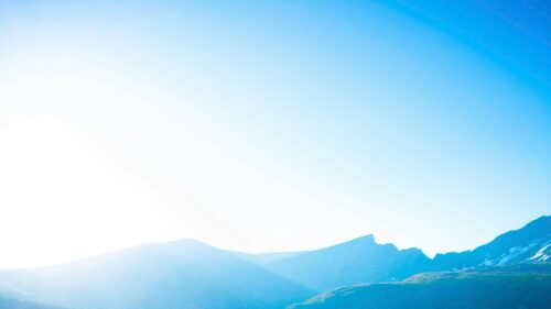 Sun-Kissed Alpine Peaks Under Clear Blue Sky 4K Desktop Wallpaper