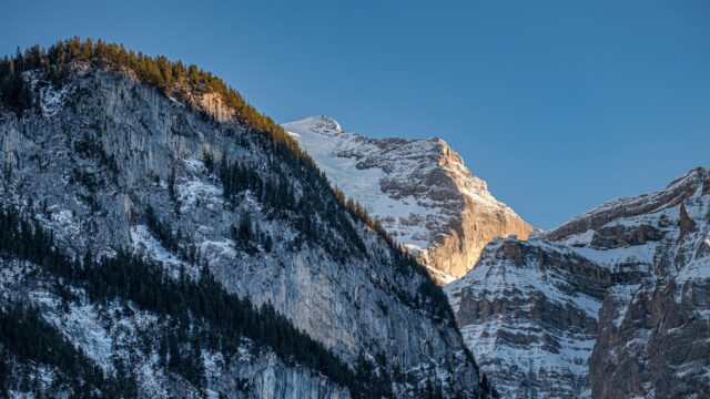 Sunlit Snowy Alpine Mountain Peak Against Clear Blue Sky 4K Wallpaper
