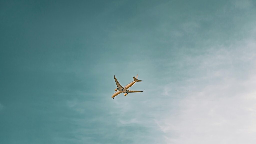 Minimalist Passenger Airplane Soaring Through Calm Blue Sky 4K Wallpaper