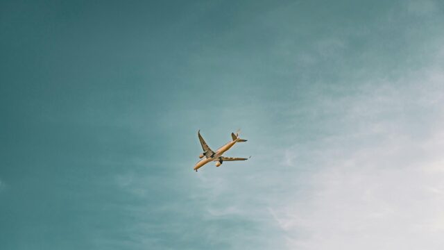 Minimalist Passenger Airplane Soaring Through Calm Blue Sky 4K Wallpaper
