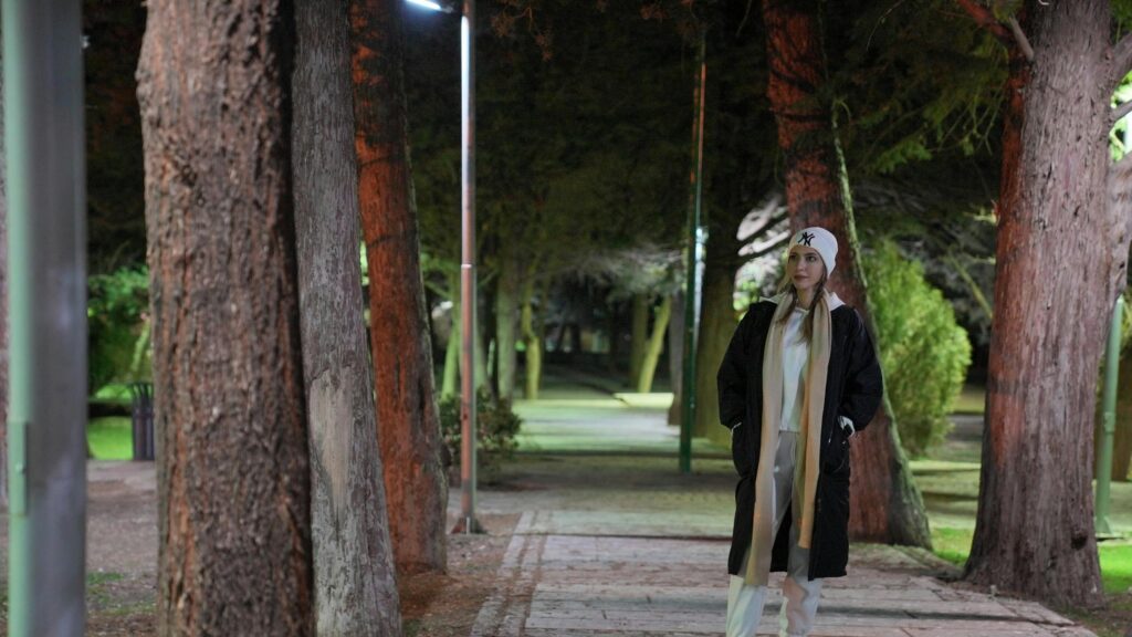 Young Woman Walking in Night Park Under Tree Lights 4K Wallpaper