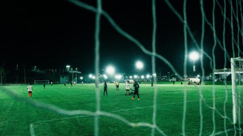 Night Soccer Match Seen Through Goal Net 4K Wallpaper