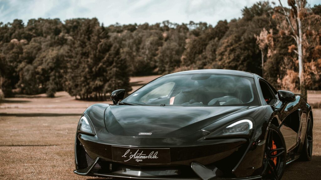 Sleek Black McLaren Sports Car Parked on Countryside Grass 4K Wallpaper