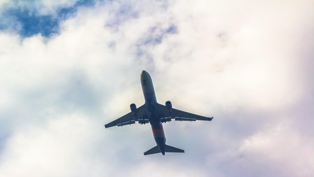 Low-Angle View of a Passenger Jet Soaring Through Clouds Desktop Wallpaper