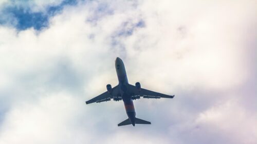 Low-Angle View of a Passenger Jet Soaring Through Clouds Desktop Wallpaper