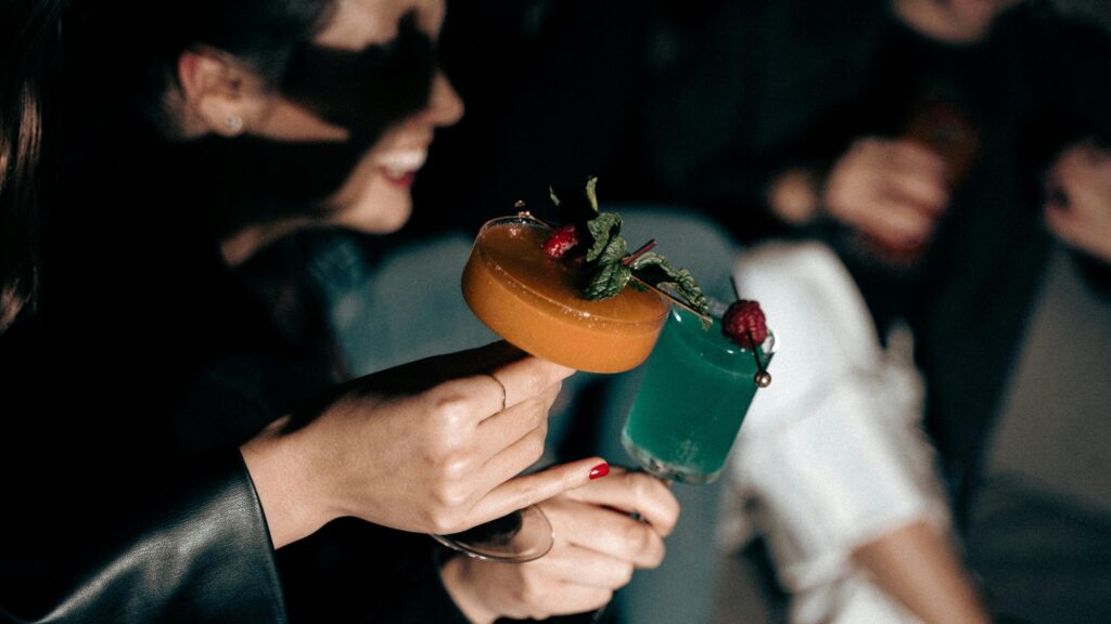 Woman Holding Vibrant Cocktails at an Evening Party 4K Wallpaper