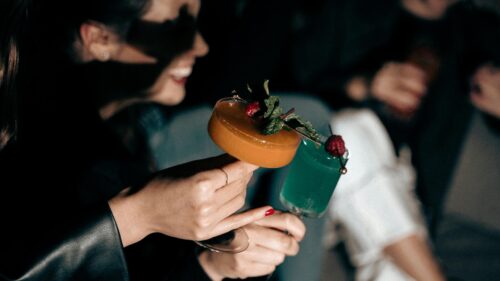 Woman Holding Vibrant Cocktails at an Evening Party 4K Wallpaper