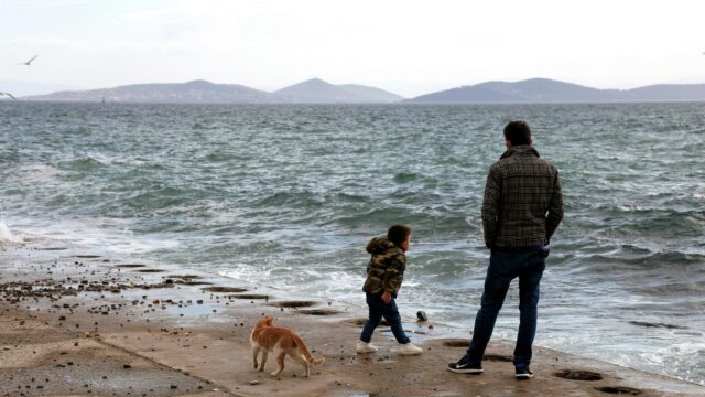Father and Son with Cat on Seawall Scenic Ocean View Desktop Wallpaper